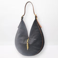 Round sculptural shoulder bag in dark brown cowhide with gold-brass hardware and signature closing system, handmade by Patricia Bos Designs.